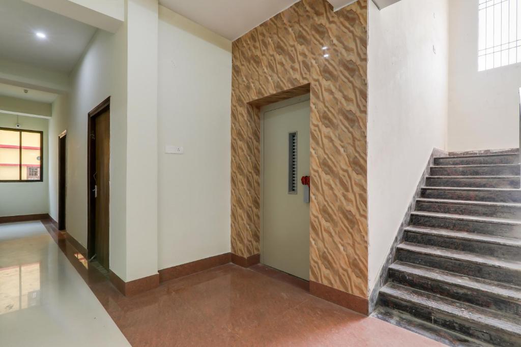 a hallway with a staircase and a wall with a door at Hotel O White House in Patna