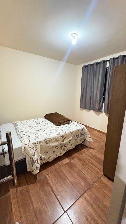 a bedroom with a bed and a wooden floor at Apart Serra Azul in Santa Bárbara