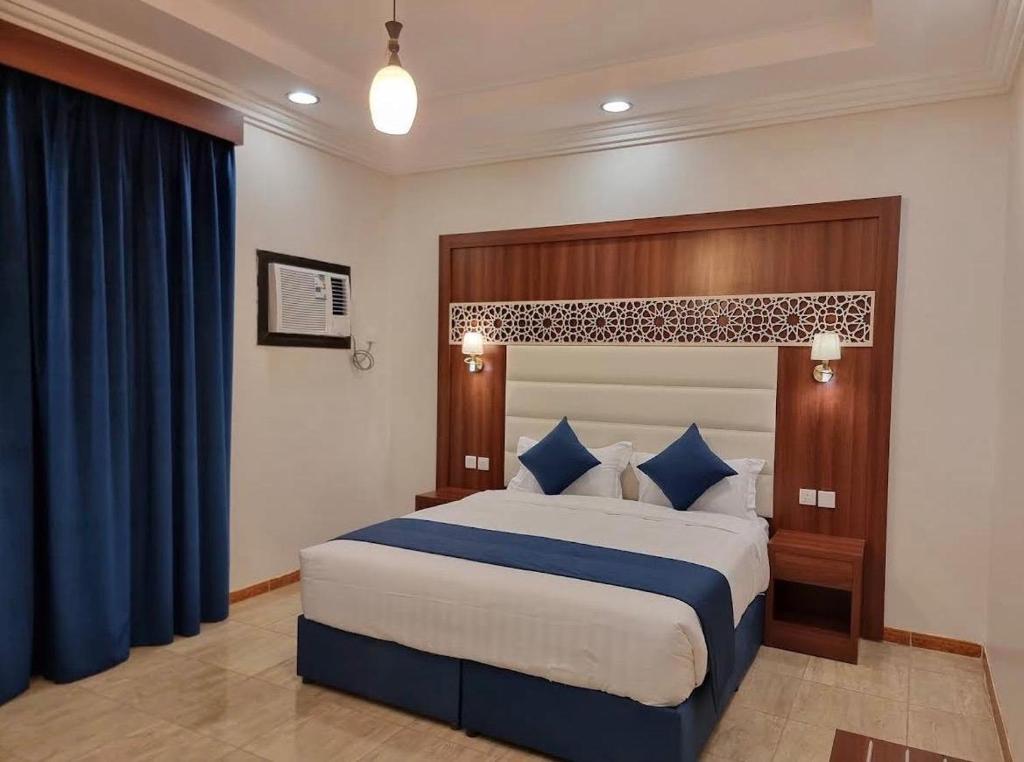 a bedroom with a large bed with blue pillows at ALdyar - Al Qunfudhah in Al Qunfudhah