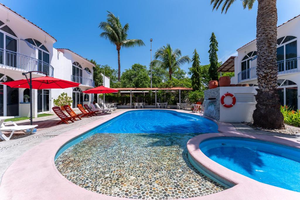 a swimming pool in front of a house with palm trees at Hotel Mexico Lindo in Santa Cruz Huatulco