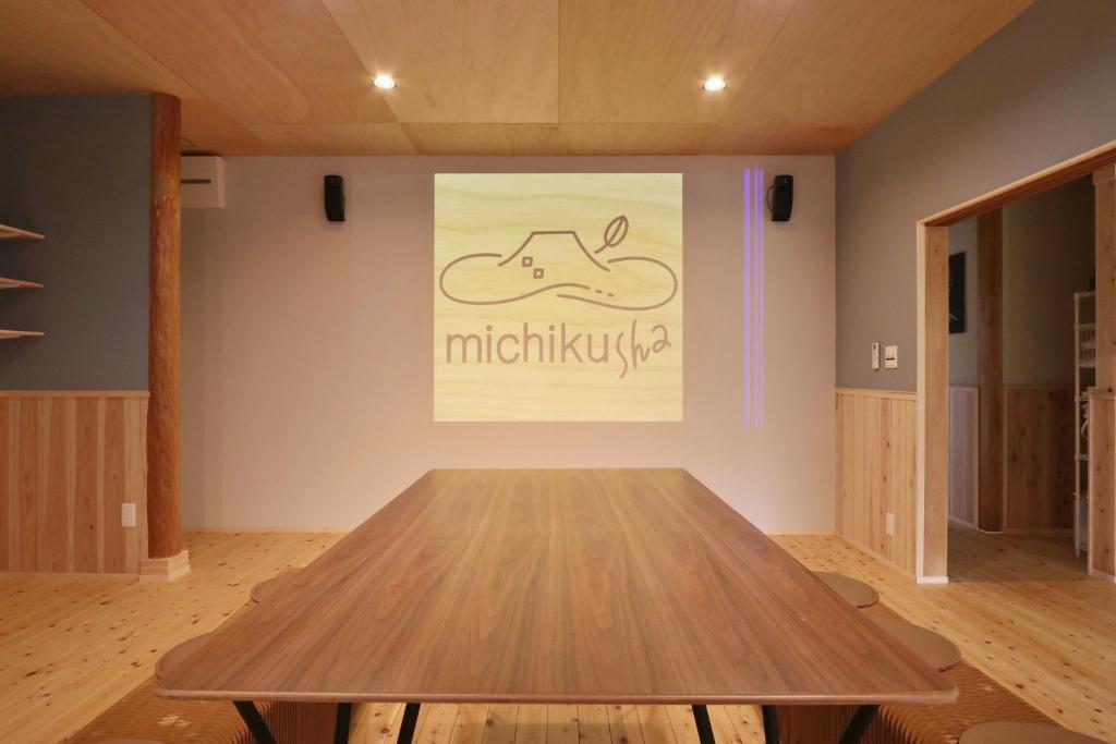 ein Holztisch in einem Raum mit einem Gemälde an der Wand in der Unterkunft michikusha in Maniwa