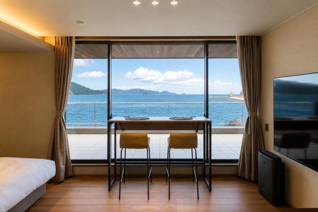 a room with a table and two chairs in front of a window at Villa JacoO-ヴィラじゃこまる- in Sanuki