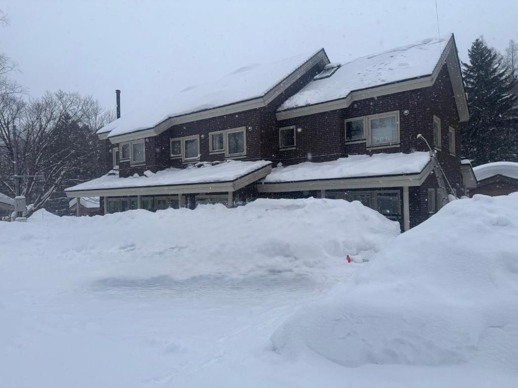 a house covered in snow with a pile of snow at Wakaranai Lodge Tomamu in Shimukappu