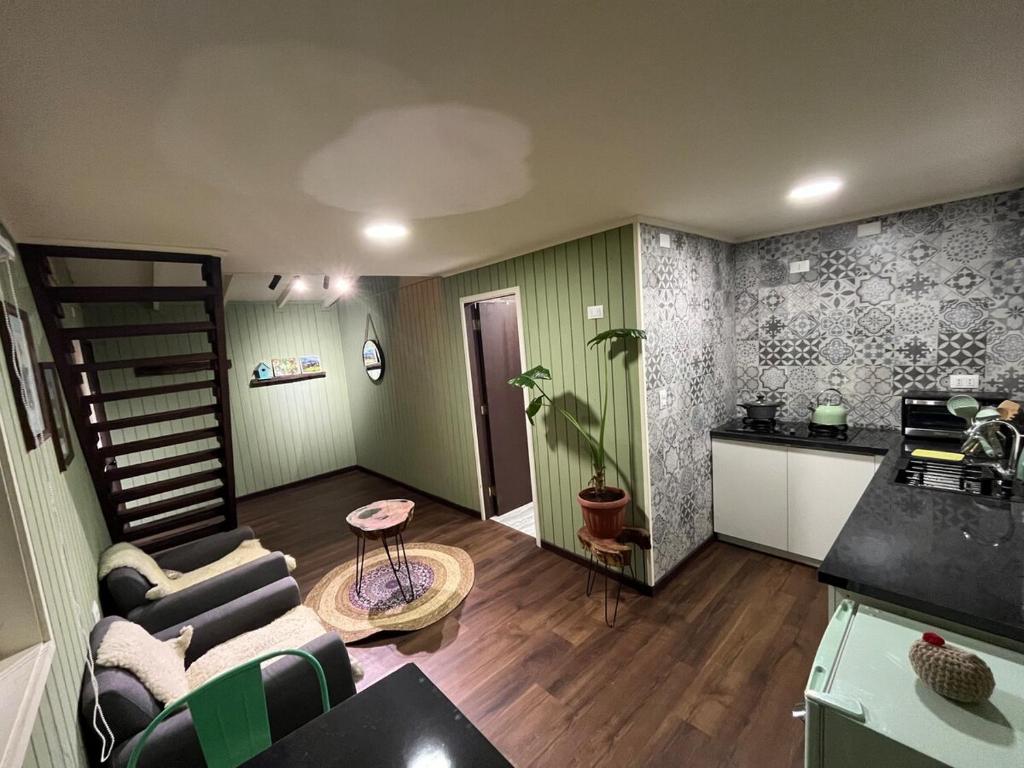 a living room with a couch and a kitchen at Casita Nalca in Chaitén