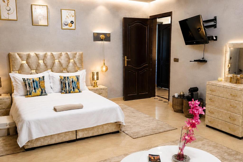 a bedroom with a large bed and a television at Appartement Spacieux 2 Chambres avec vue sur le jardin - Taroudant in Taroudant