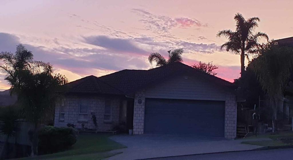 a house with a garage in front of a sunset at Sunset Te Kamo in Whangarei