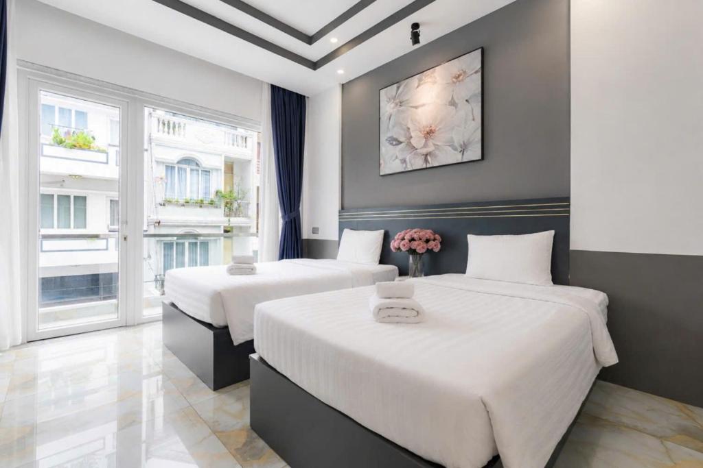 a bedroom with two beds with white sheets at GALANG HOTEL in Ho Chi Minh City