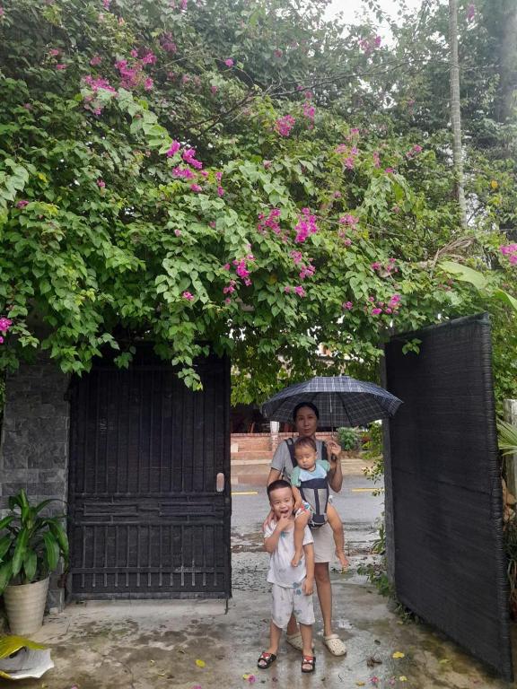 a woman and two children standing under an umbrella at Lockhang homestay in Thanh Ðông (1)
