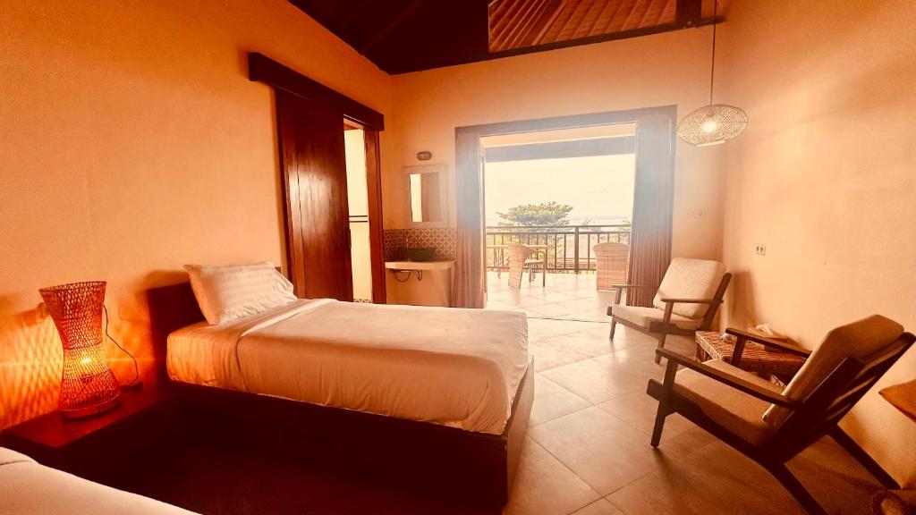 a bedroom with a bed and a chair and a balcony at Sanur ocean view villas in Sanur