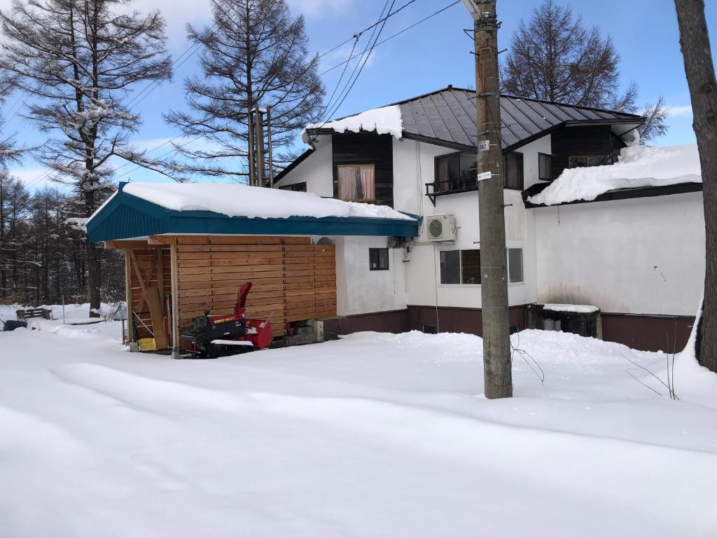 a building with a blue awning in the snow at Alpha Live Madarao in Madarao Kogen