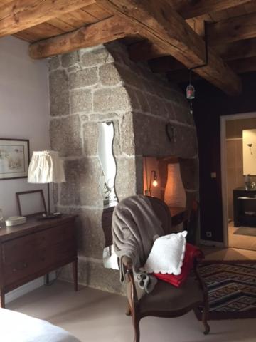 una chimenea de piedra en una habitación con silla en La ferme de Félix en La Chaze-de-Peyre