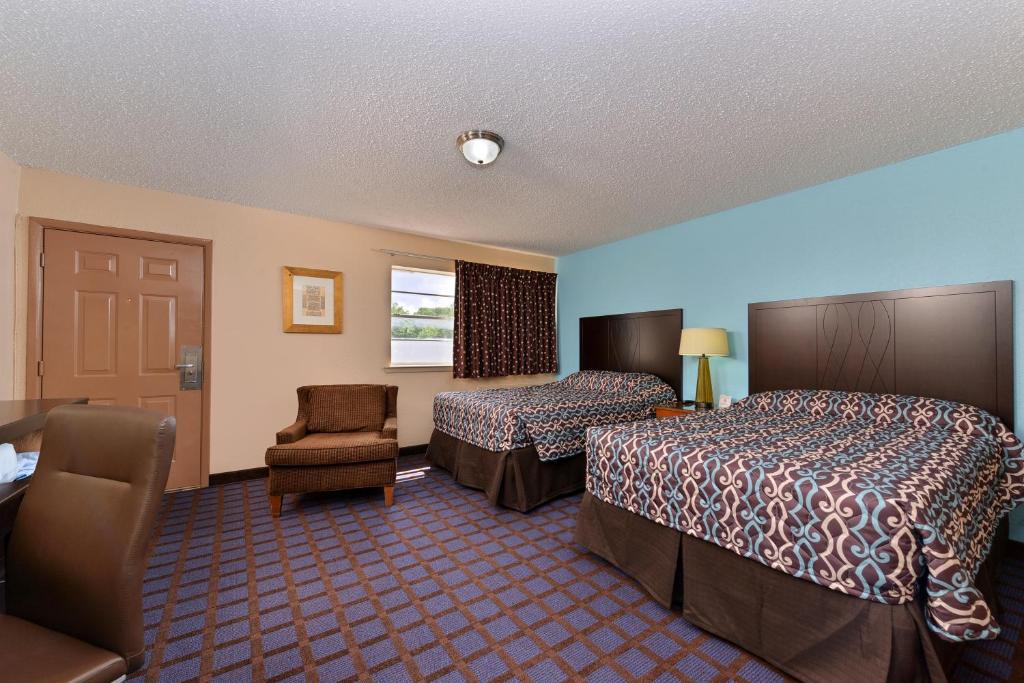 a hotel room with two beds and a chair at Economy Inn Ardmore in Ardmore