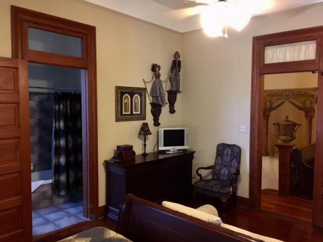 a living room with a tv and a desk with a chair at 1896 O'Malley House in New Orleans