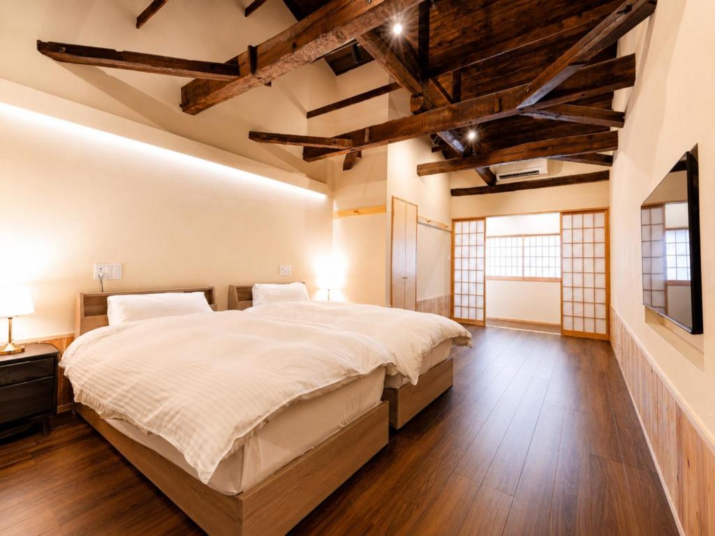 a bedroom with a large bed and wooden floors at 奈良旅館 VILLA East West in Nara