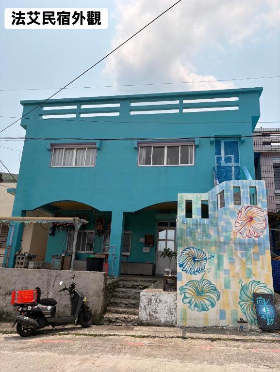 a blue building with a scooter parked in front of it at 法艾民宿 in Yeh-yin