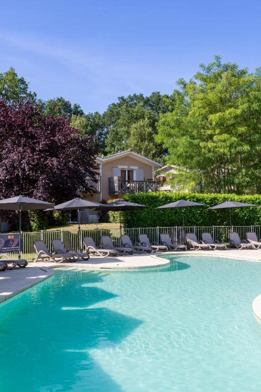 a swimming pool with lounge chairs and umbrellas at Appartement T3 Golf Albret in Barbaste