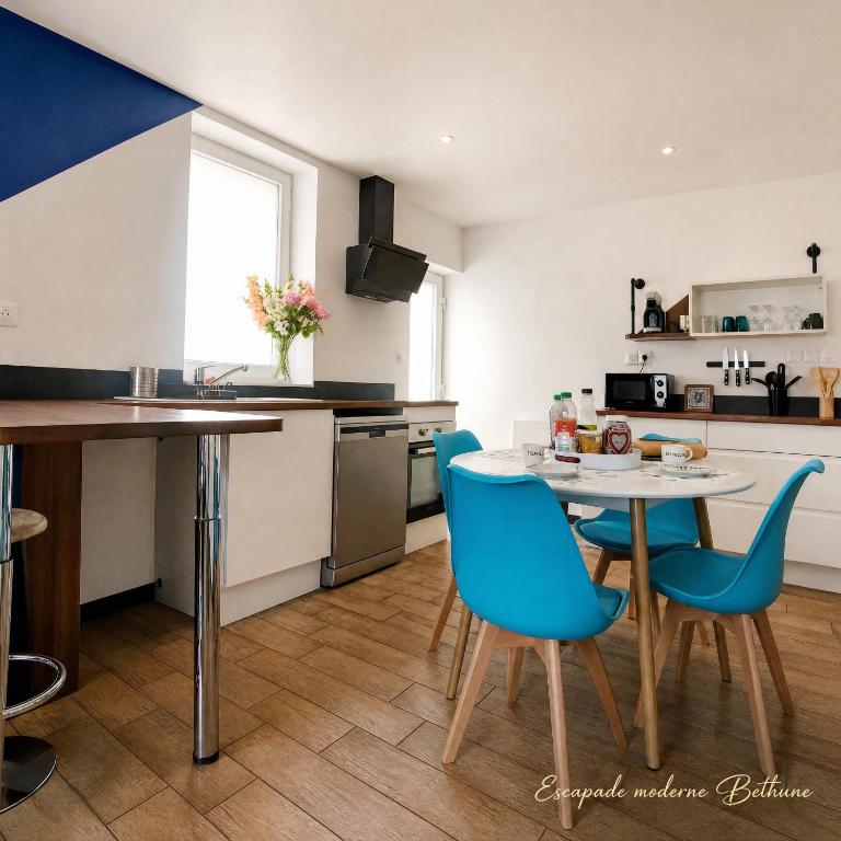 a kitchen with a table and blue chairs at Jardin clos et terrasse exterieure, Maison plein pied Béthune, PARKING, quartier calme proche centre ville, proche gare, capacité 4 personnes in Béthune