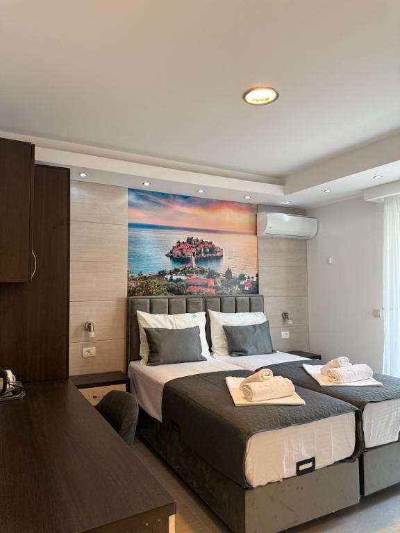 a bedroom with two beds and a painting on the wall at Apartments Vé in Budva