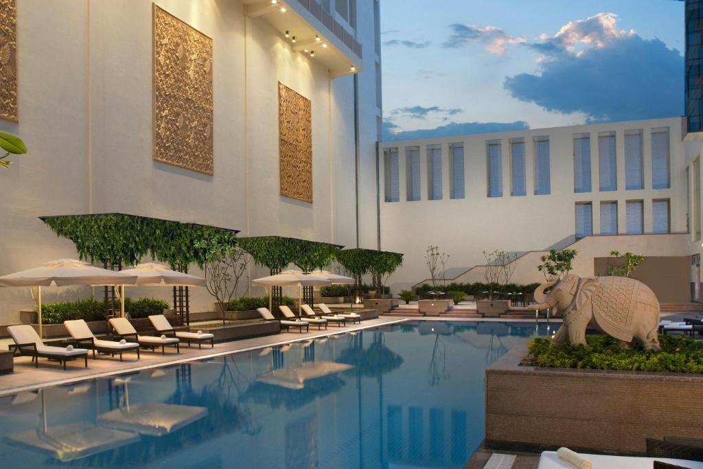 a hotel swimming pool with chairs and an elephant statue at Jaipur Marriott Hotel in Jaipur