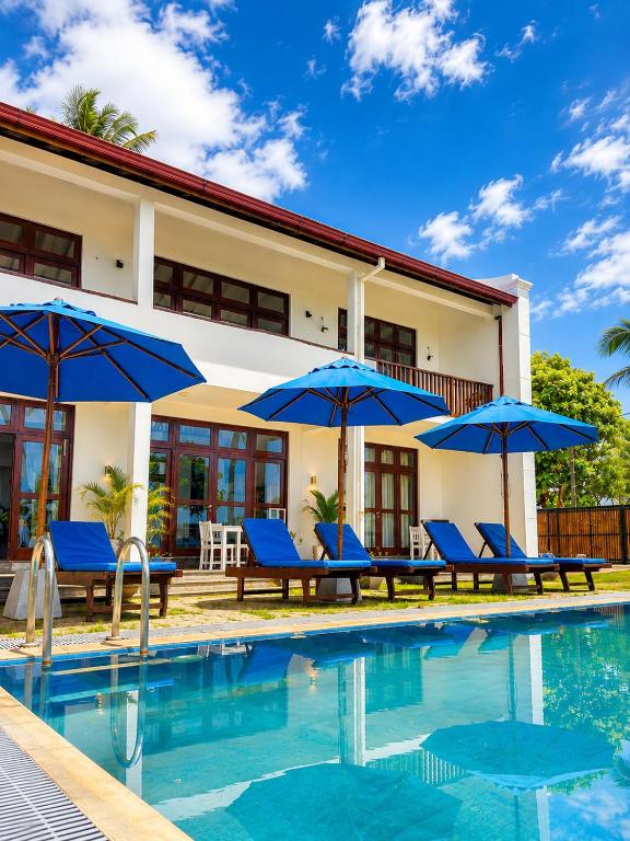 a villa with a swimming pool and blue umbrellas at Surf Bay Villa Weligama in Pelena