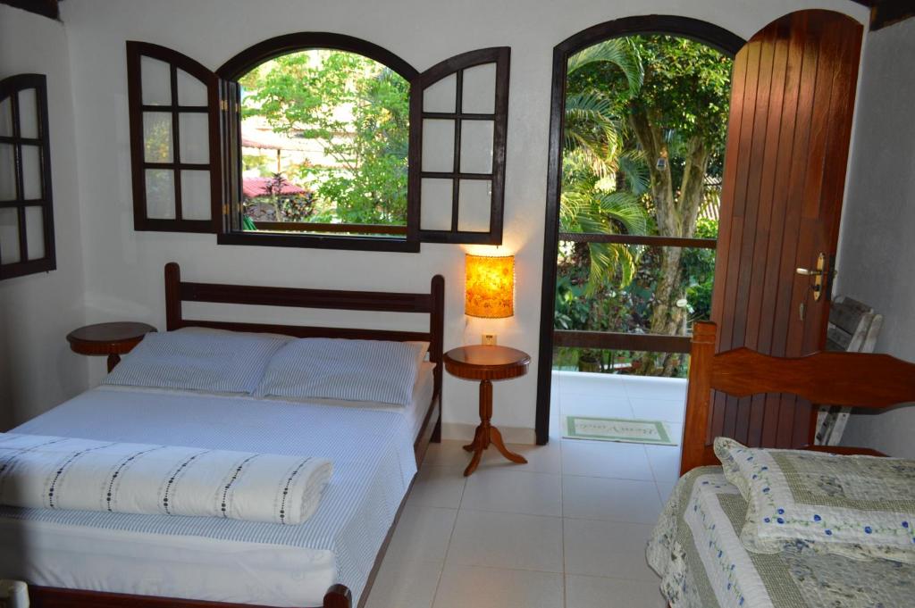 a bedroom with a bed and two windows at Recanto das Flores Lofts - Ilha Grande Rj in Abraão