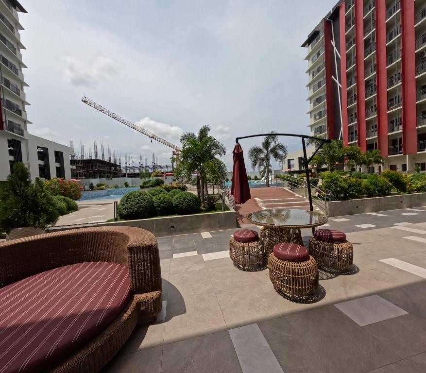 a patio with a glass table and chairs and a table with a umbrella at Cozy 1BR Prime World District, Near Airport, Gaisano Grand Mall, Mactan Doctor's Hospital in Agus