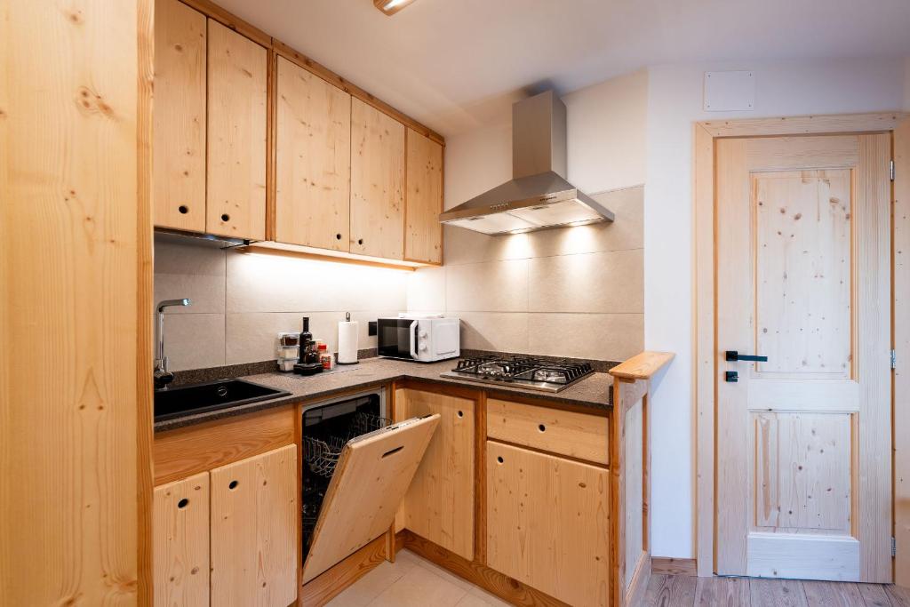 a kitchen with wooden cabinets and a stove top oven at Dolomitihouse NOGHERA in Fiera di Primiero