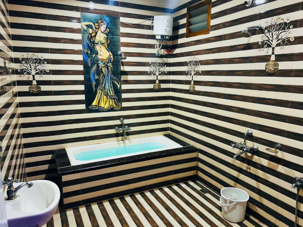 a bathroom with a tub with a painting on the wall at Sandunes ReTreat Villa in Pondicherry