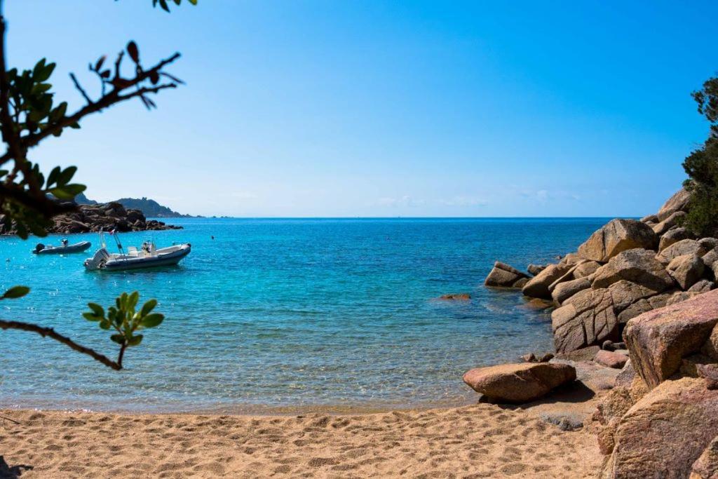a boat in the water on a rocky beach at Locations proche de la plage de Barcaggio accessible par une piste en terre de 3,5 kilometres de Tizzano en voiture in Sartène