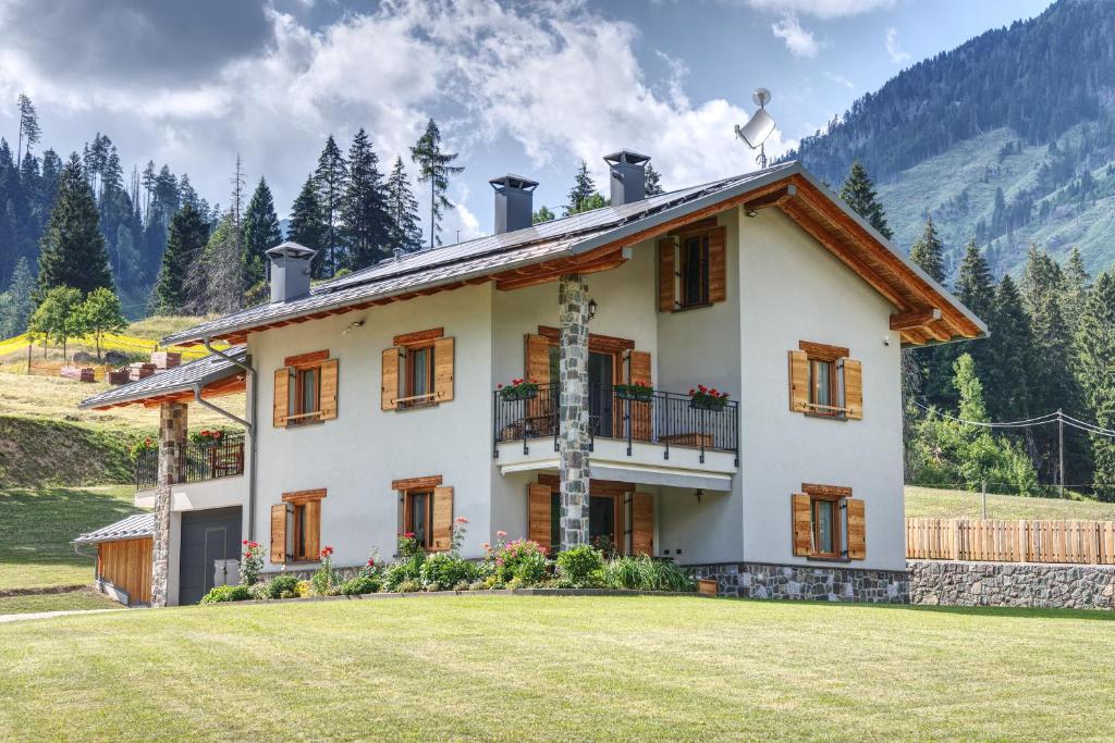a house with a grass yard in front of it at Baita PUPILLE in Osteria Alpina
