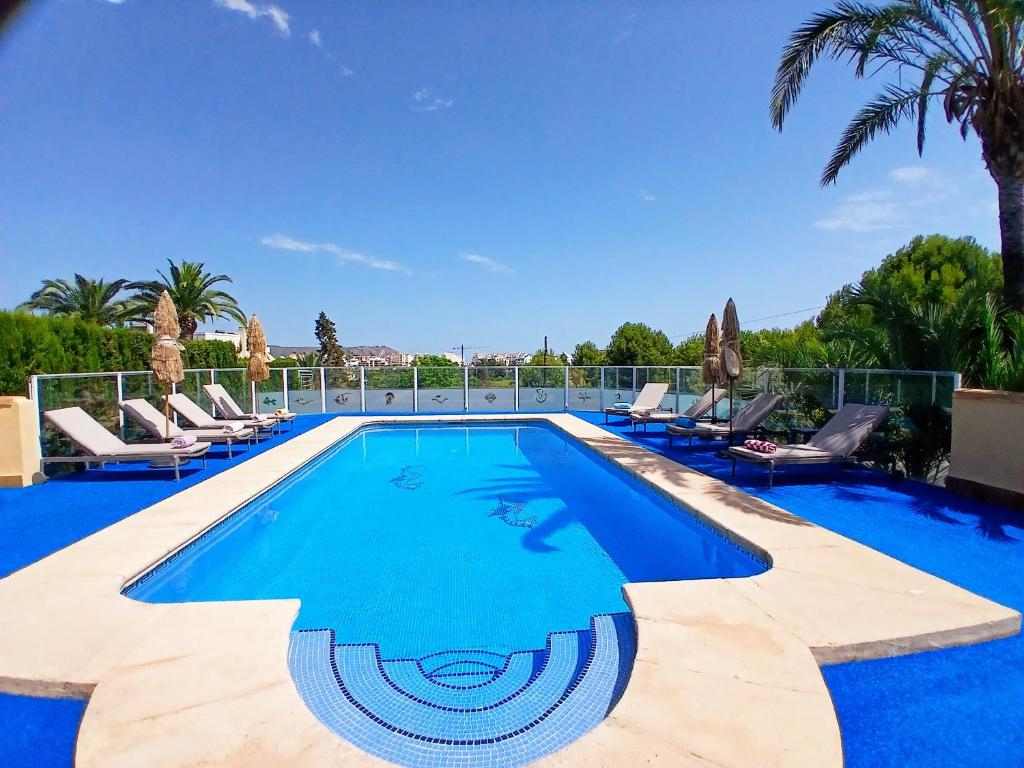 a swimming pool with lounge chairs and palm trees at Villa Gota de Mar in Jávea