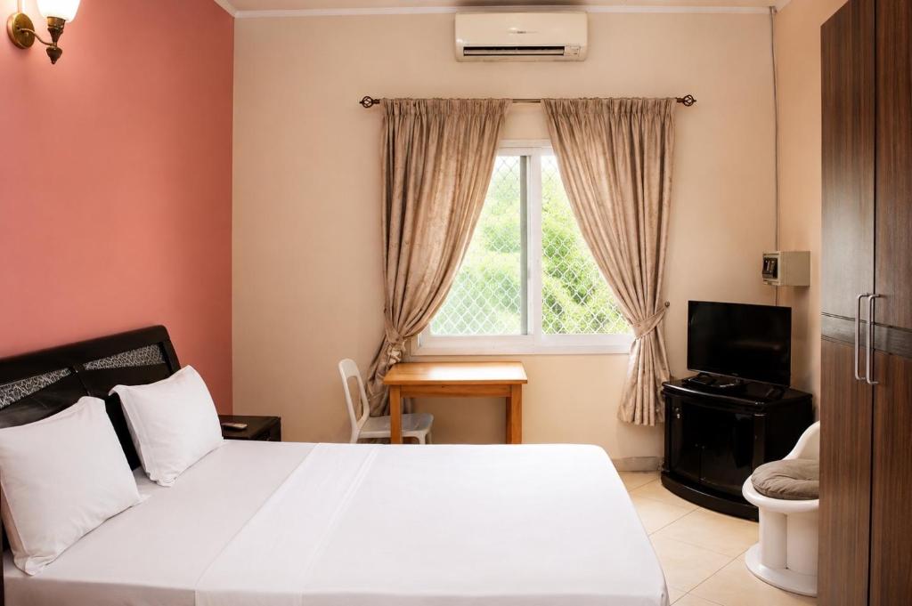 a bedroom with a white bed and a window at Chambre à louer in Moroni