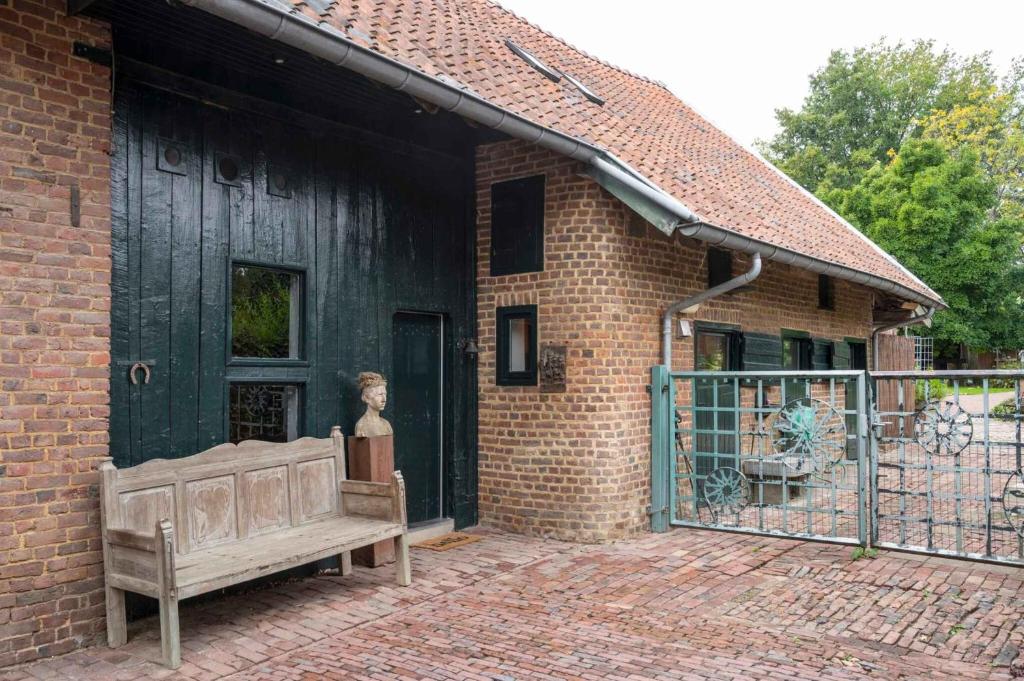 a wooden bench sitting in front of a brick building at Op de Klever in Schimmert
