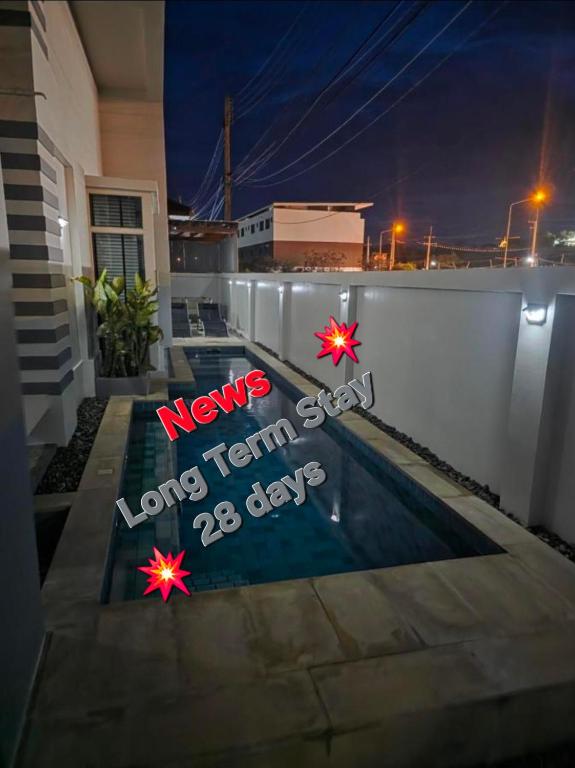 a swimming pool with a sign on the side of a house at Pranaluxery Pool Villa 1 in Pran Buri