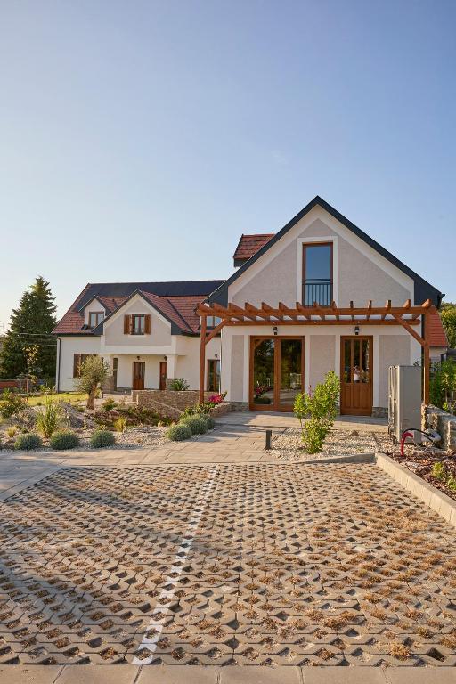 a house with a cobblestone driveway in front of it at Villa Olea in Tihany