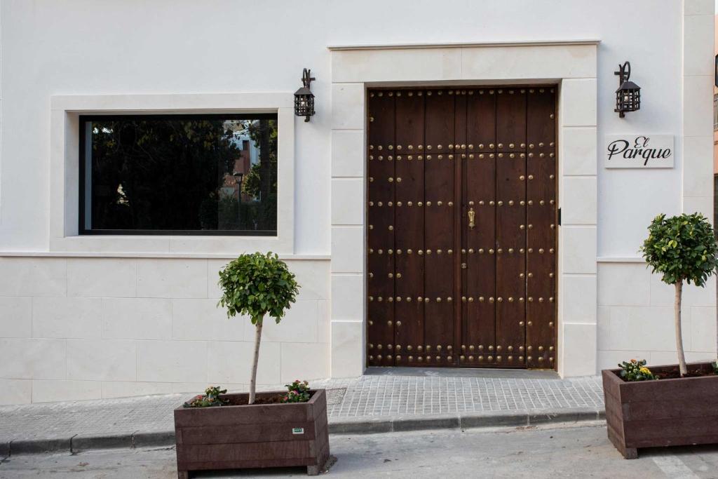 two potted trees in front of a wooden door at Alojamientos El Parque in Rute