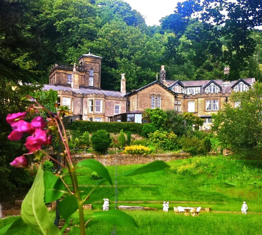 
a house with a flower garden in front of it at Harefield Hall in Pateley Bridge
