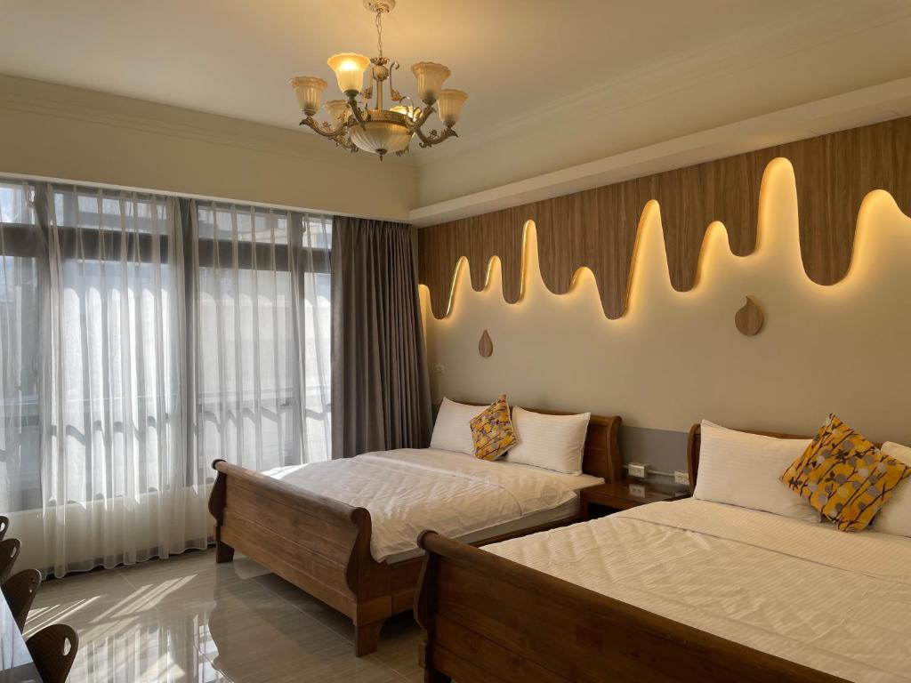 a bedroom with two beds and a chandelier at 好客來-正市區電梯別墅步行東大夜市3分鐘公正包子1分鐘 in Hualien City