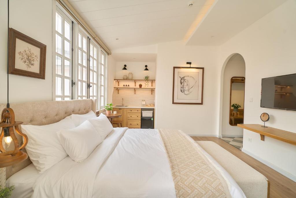 a bedroom with a white bed and a kitchen at Hanachi Stay in Ho Chi Minh City