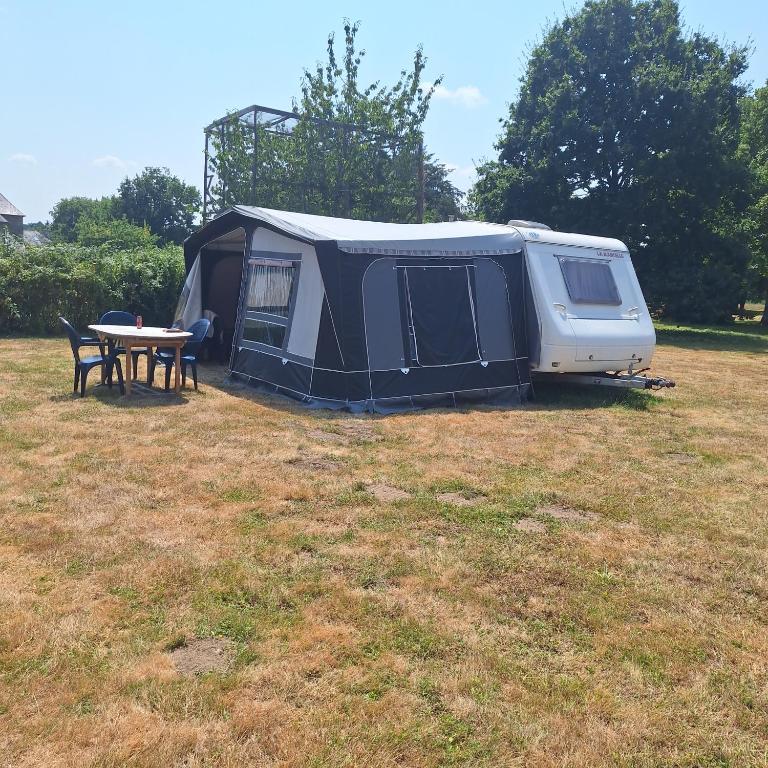 a tent and a picnic table in a field at Caravane Les Roches Blanches in Guenroc