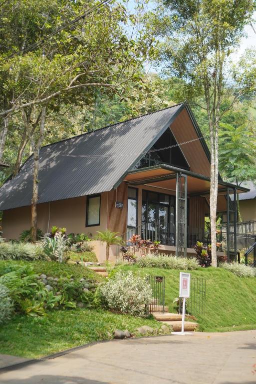 a house with a black roof in a yard at Teras Bumi Cabin in Haurkuning