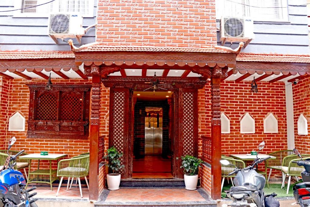 ein rotes Backsteingebäude mit Tischen, Stühlen und Motorrädern. in der Unterkunft Hotel Malati in Kathmandu