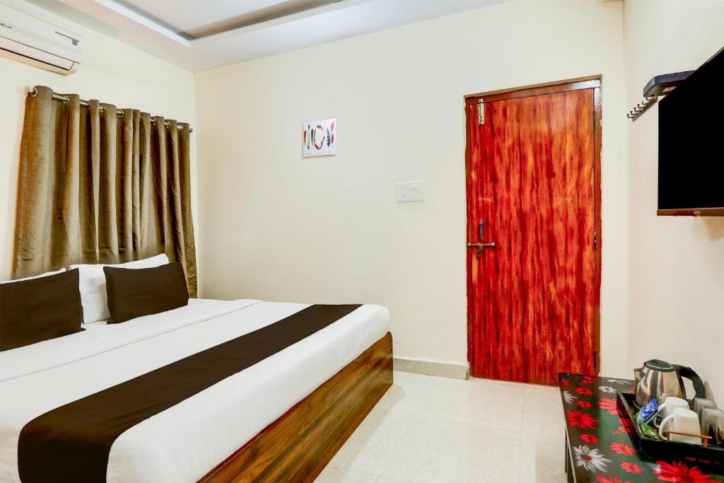 a bedroom with a bed and a red door at Hotel O Vyb Hotels in Hyderabad