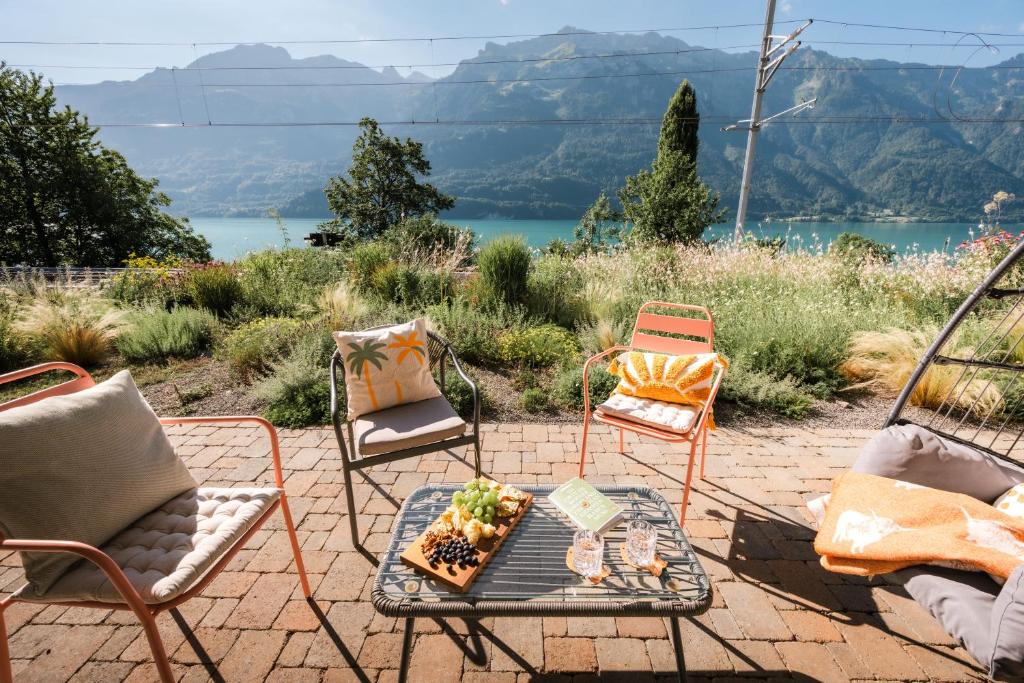 a patio with chairs and a table with a plate of food at FLORA BAY Spacious Lake and Mountain View Apartment in Niederried