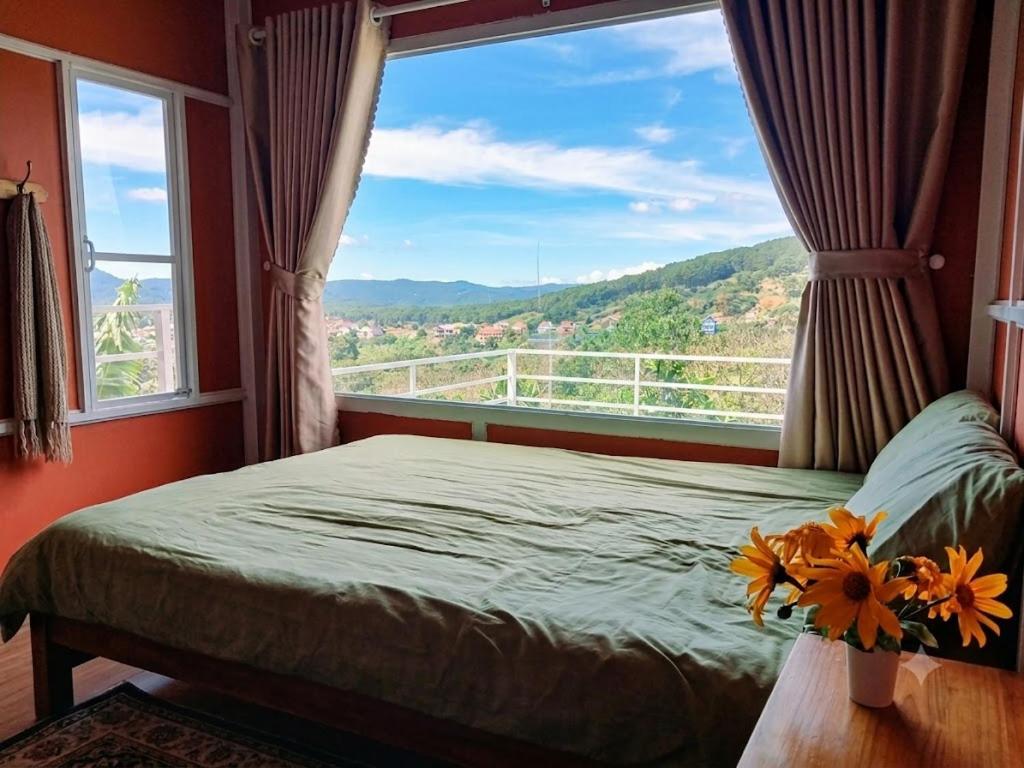 a bedroom with a bed and a large window at Homestay Đồi Sương Trắng in Da Lat