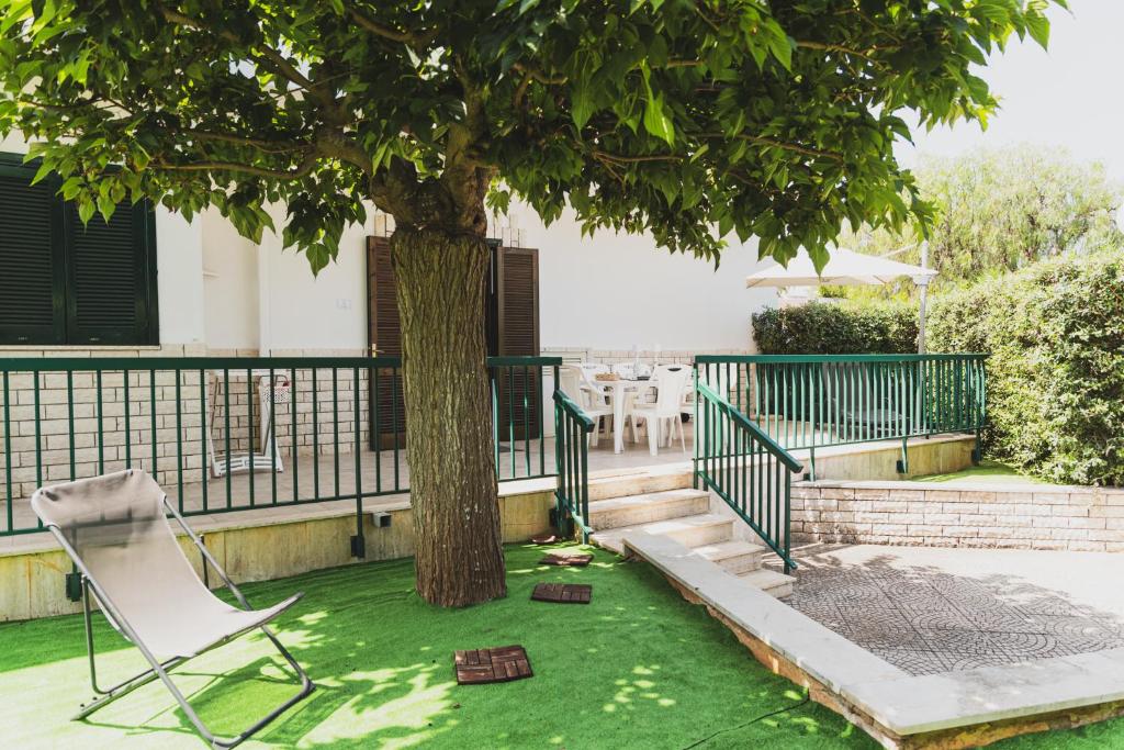a chair sitting under a tree in a yard at Villa Zoe in Specchiolla