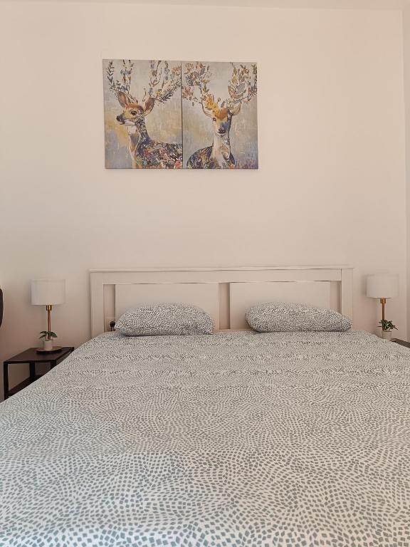 a bedroom with a bed with two deer paintings on the wall at Studio apartman - Sweet&Little in Vrbovec