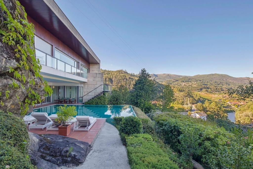 a house with a swimming pool next to a mountain at Infinity Villa Cavez - Luxury Retreat in Moimenta