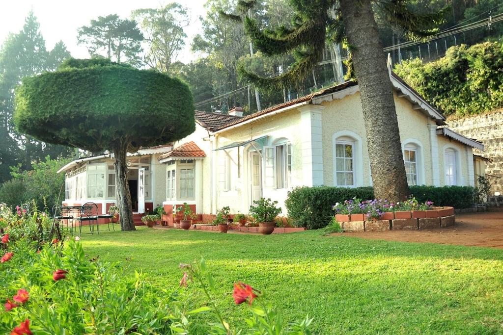 a house with a large tree in the yard at Wyoming Heritage in Ooty