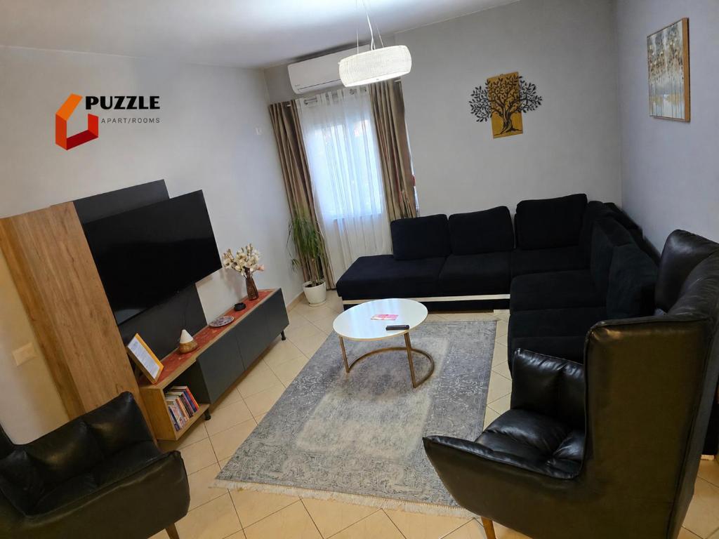 a living room with a couch and a tv at Puzzle Apart Rooms in Tirana